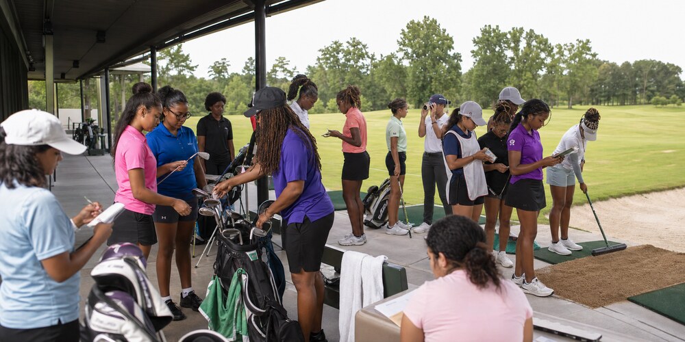 Junior players training with yardage and support equipment at a HERitage Golf Tour clinic